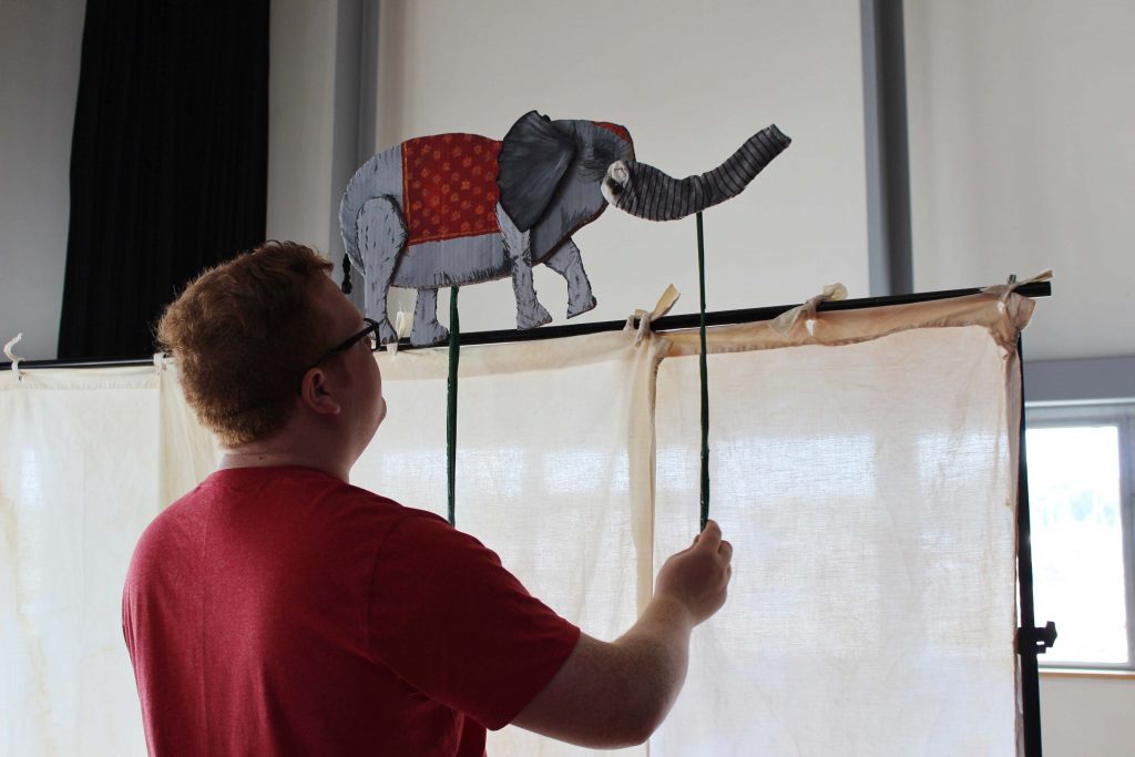 An elephant puppet walking along a screen