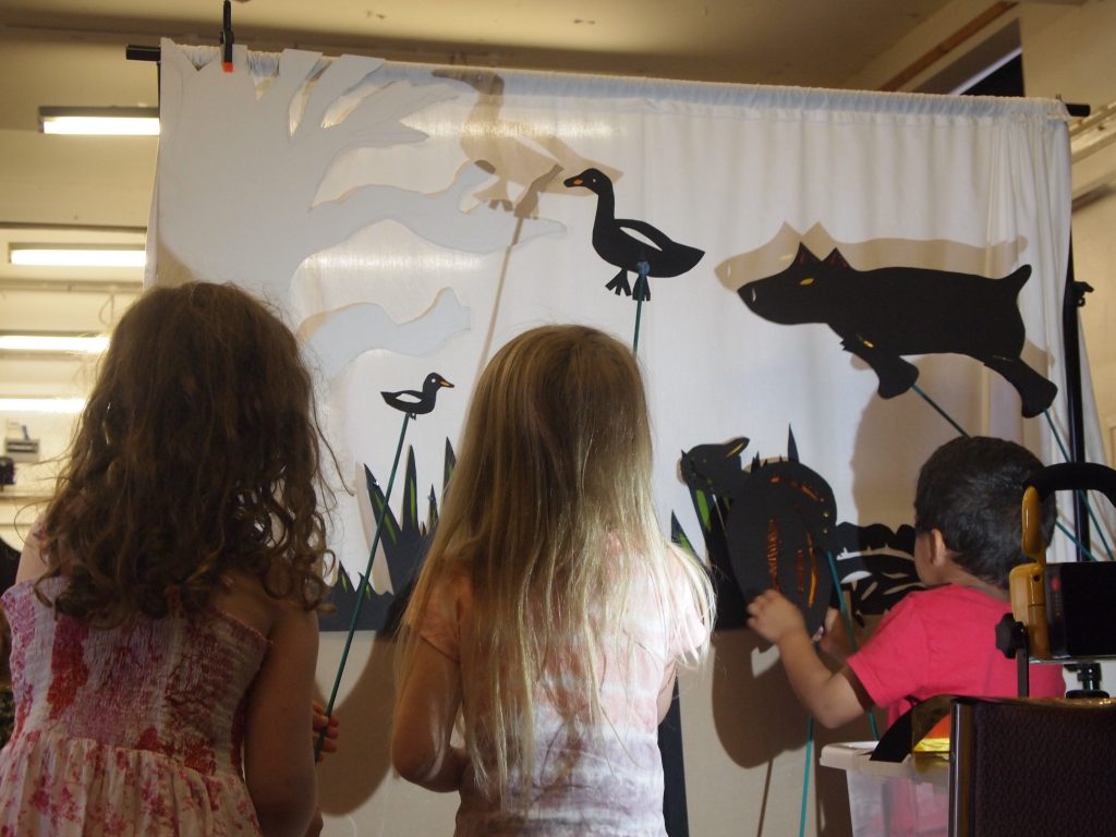 Children holding a shadow puppet of a duck and a dog